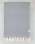 Folded handwoven extra-large blanket with a chevron pattern in grey colour.