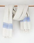 Beige linen scarf with a cotton blend and blue colour stripes with knotted fringe and hand-twisted style on the stick.
