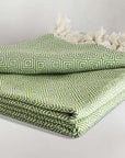 Stylish folded handwoven large-size blanket with a diamond pattern in green colour.