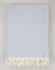 Folded handwoven large-size blanket with a diamond pattern in light grey colour.