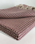 Stylish folded handwoven cotton blanket with an eye-shaped pattern in burgundy & beige colour.