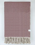 Folded handwoven cotton blanket with an eye-shaped pattern in burgundy & beige colour.