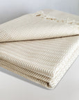 Stylish folded soft cotton blanket with a gentle waves pattern in beige colour.