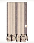 Folded towel with thin and thick colourful vertical stripes and hand-twisted & knotted fringe.