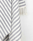 Close-up image of the cotton towel with navy stripes and hand-twisted & knotted fringe.