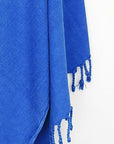 Close-up image of beach towel in plain blue colour with knotted fringe.