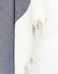 Close-up image of a diamond pattern towel in navy colour with knotted fringe.