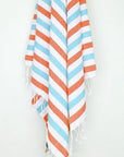 Towel with orange & blue horizontal stripes and hand-twisted & knotted fringe hanging.