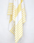 Beach towel with yellow and white colours stripes and knotted fringe hanging.