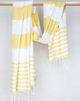 Beach towel with yellow and white colours stripes and knotted fringe with hand-twisted style on the stick.