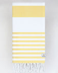 Folded beach towel with yellow and white colours stripes and hand-twisted & knotted fringe.