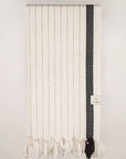 Folded towel with black stripes on beige colour and knotted fringe.