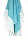 Towel in sea green colour with horizontal stripes and knotted fringe hanging.