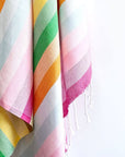 Close-up image of a towel with thick colourful stripes and hand-twisted & knotted fringe.