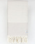 Folded a beige colour towel with white stripes and knotted fringe.