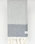 Folded a black colour towel with white stripes and knotted fringe.