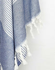 Close-up image of a denim colour towel with white stripes and knotted fringe.