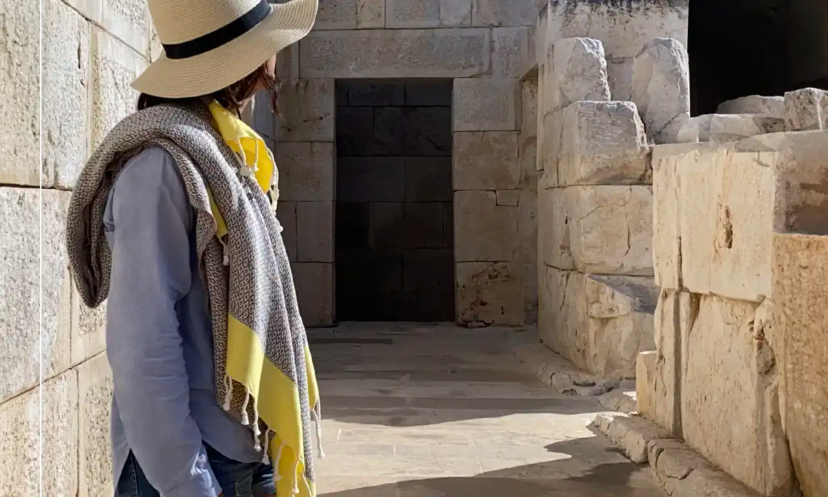 woman standing in history's site with yellow turkish peshtemal towel over the shoulder with tassels