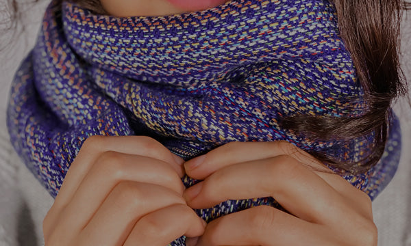 Close-up image of a super soft scarf wrapped around a model's neck and hands.
