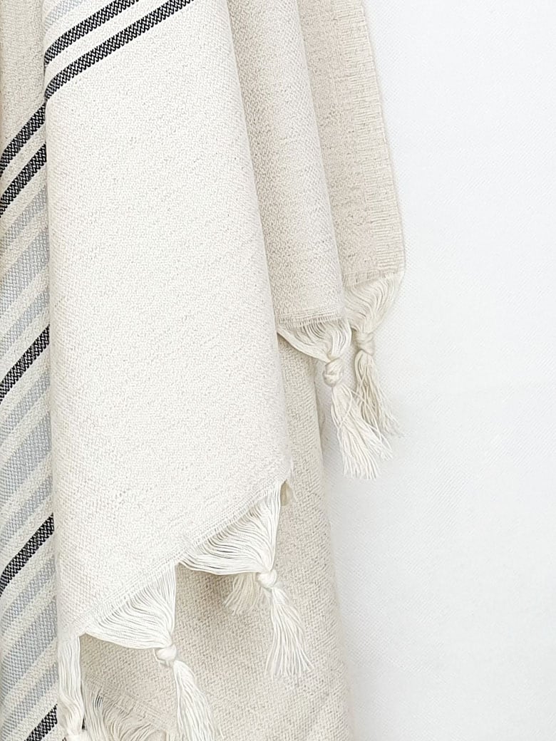 Close-up image of grey stripes on a cream colour plain colour with linen & cotton blends with knotted fringe.