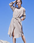 Front image of woman wearing beige boho midi shirt dress with beige rope belt and long sleeves.