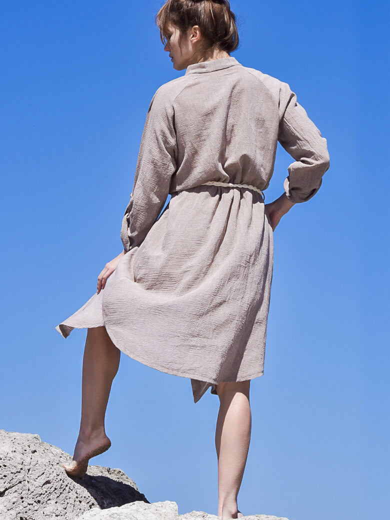 Back image of a woman wearing beige boho midi shirt dress with a beige rope belt and long sleeves.