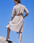 Back image of a woman wearing beige boho midi shirt dress with a beige rope belt and long sleeves.
