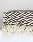 Close-up side image of a brown colour extra-large blanket with a tasselled edge.