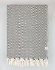 Folded handwoven extra-large blanket with a chevron pattern in brown colour.