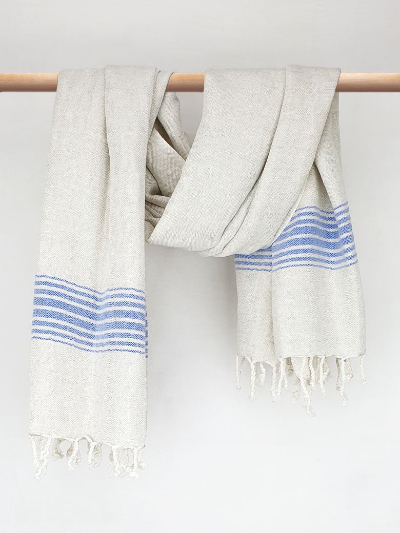 Beige linen scarf with a cotton blend and blue colour stripes with knotted fringe and hand-twisted style on the stick.