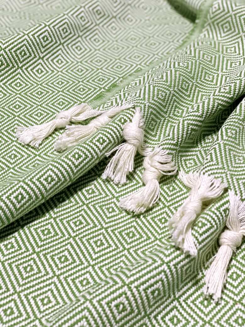 Stylish photo-shooting of a green colour large-size blanket with knotted fringe style.