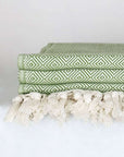 Close-up side image of a green colour large-size blanket with knotted fringe style.