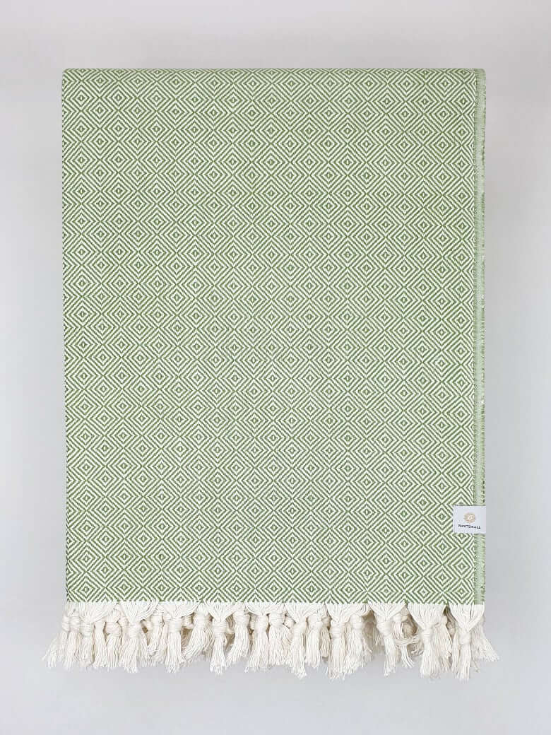 Folded handwoven large-size blanket with a diamond pattern in green colour.