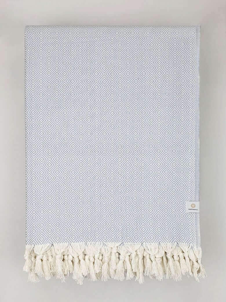Folded handwoven large-size blanket with a diamond pattern in light grey colour.