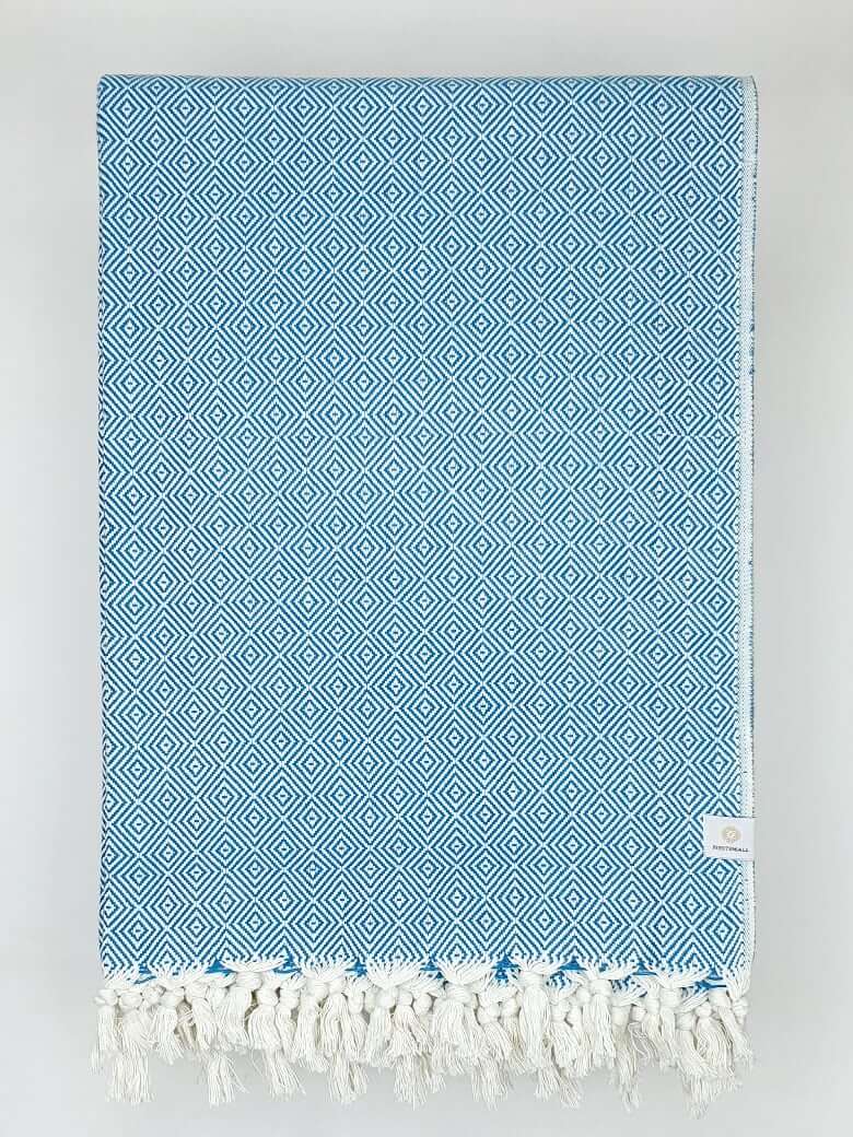 Folded handwoven large-size blanket with a diamond pattern in petrol colour.