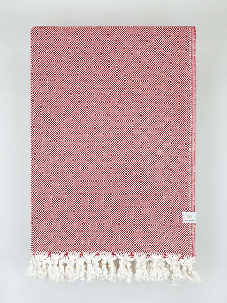 Folded handwoven large-size blanket with a diamond pattern in red colour.