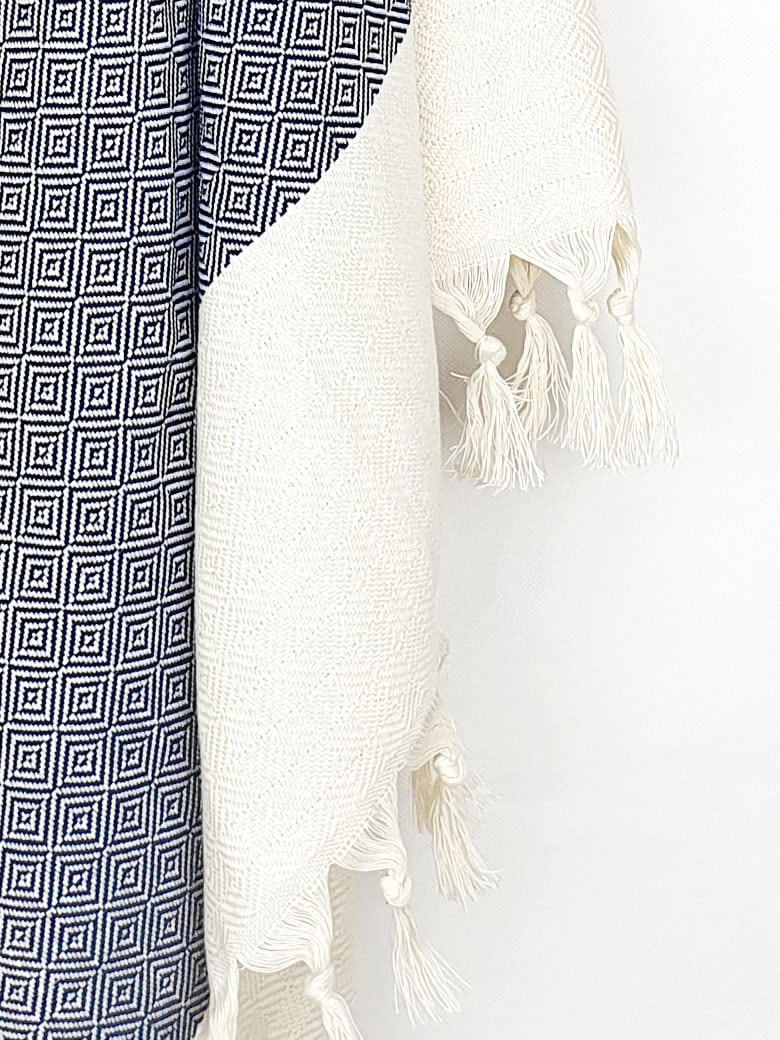 Close-up image of a diamond pattern cotton scarf in navy colour with knotted fringe.