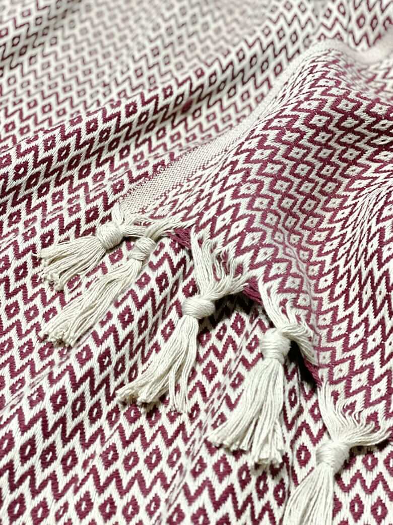 Stylish photo-shooting of a burgundy & beige colour cotton blanket with a knotted fringe.