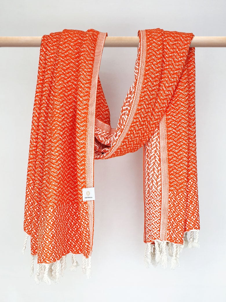 Cotton scarf in orange colour in a 'gentle wave' pattern with knotted fringe and hand-twisted style on the stick.
