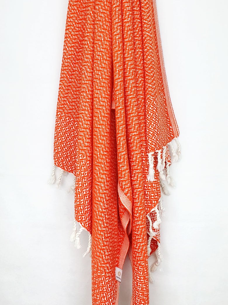 Cotton scarf in orange colour in a 'gentle wave' pattern with knotted fringe hanging.