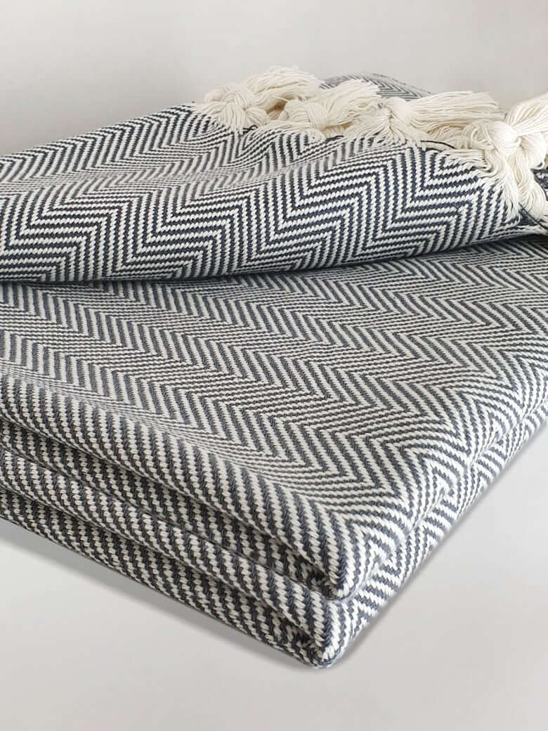 Stylish folded handwoven %100 cotton blanket with a herringbone pattern in grey colour.
