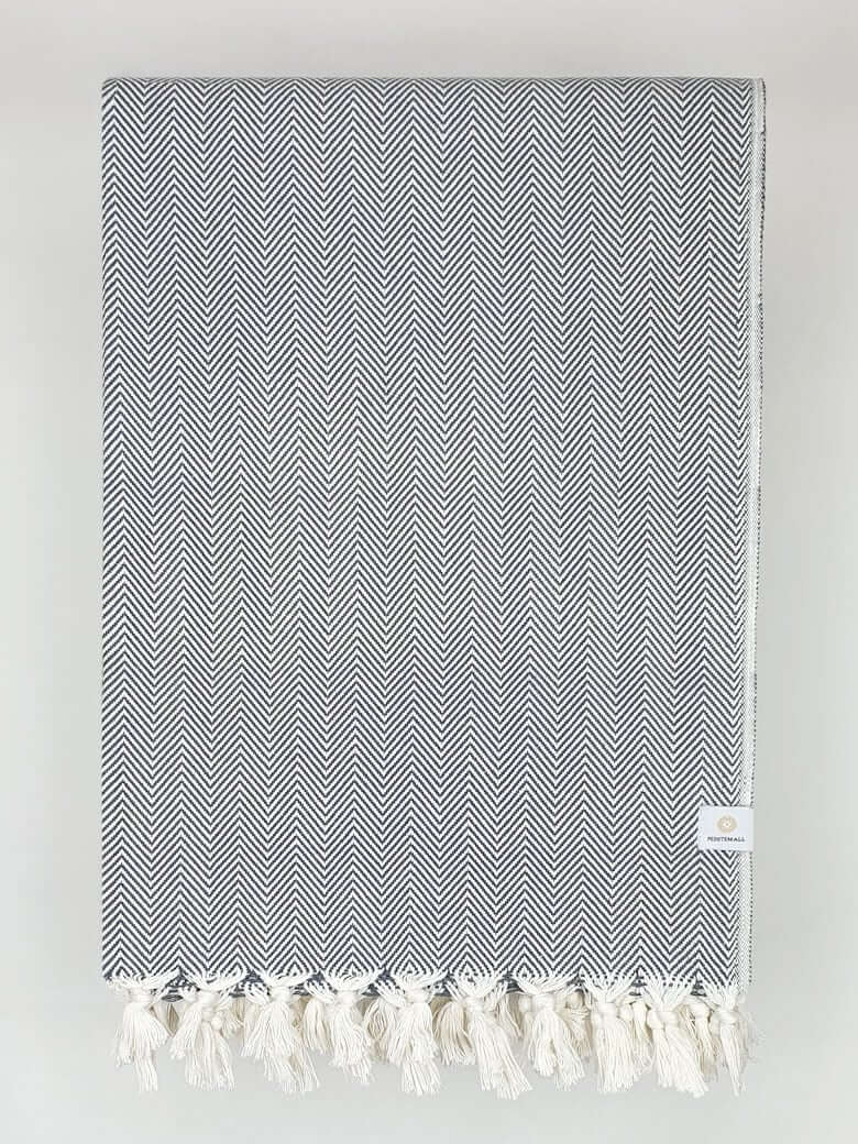 Folded handwoven %100 cotton blanket with a herringbone pattern in grey colour.
