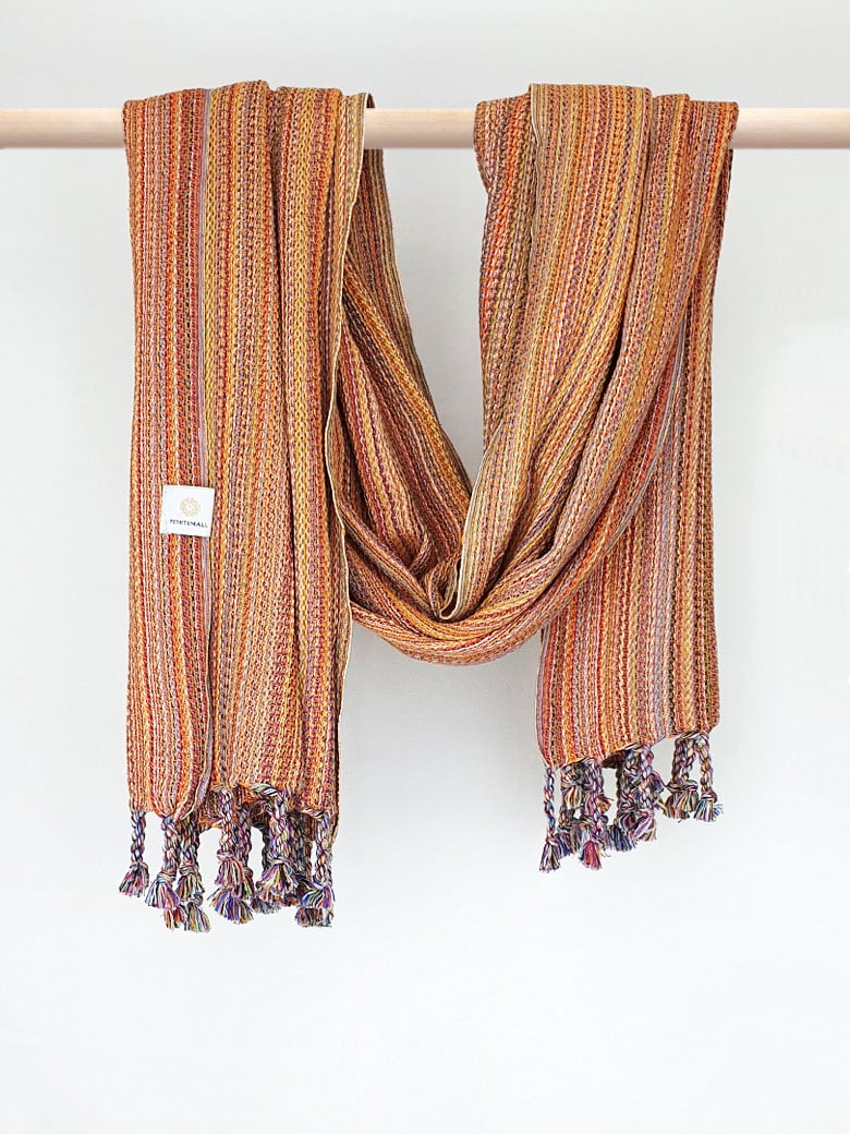 Crochet scarf with a blend of orange colours with knotted fringe and hand-twisted style on the stick.