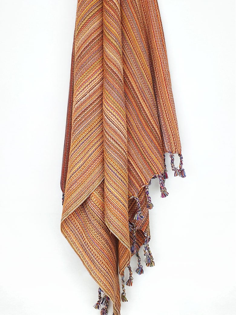 Crochet scarf with a blend of orange colours with knotted fringe hanging.
