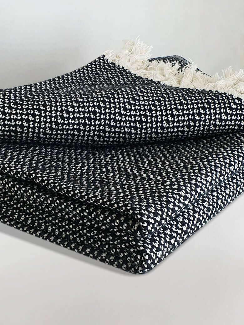 Stylish folded handwoven king-size blanket with a chain pattern in black & white colour.