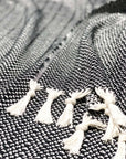 Stylish photo-shooting of a black & white colour king-size blanket with a tasselled edge.