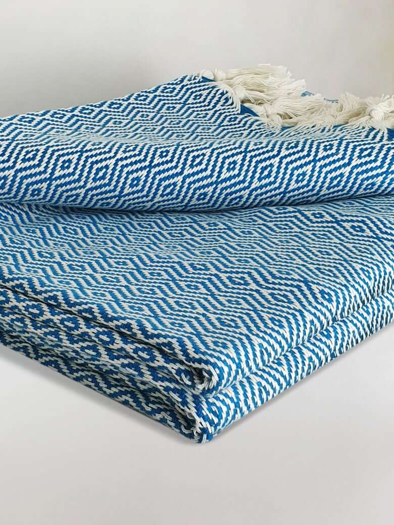 Stylish folded handwoven blanket with a pearl pattern in petrol colour.