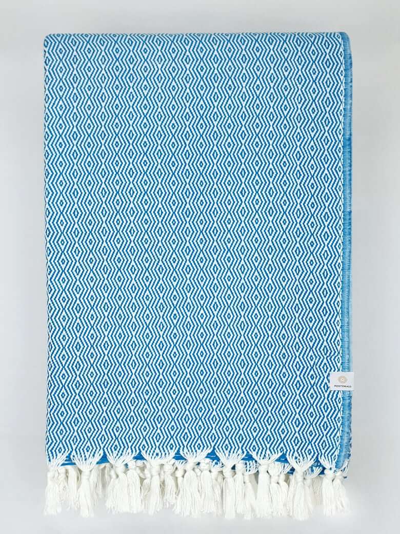 Folded handwoven blanket with a pearl pattern in petrol colour.