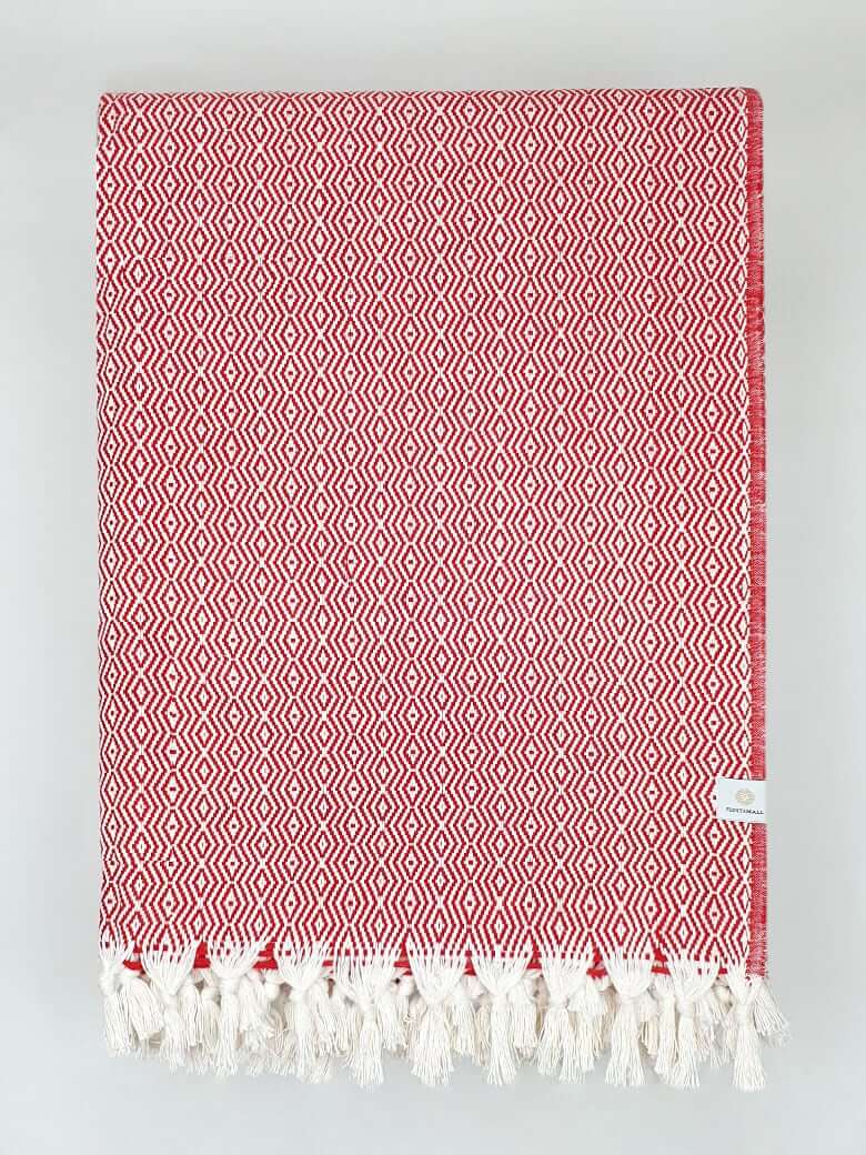 Folded handwoven blanket with a pearl pattern in red colour.