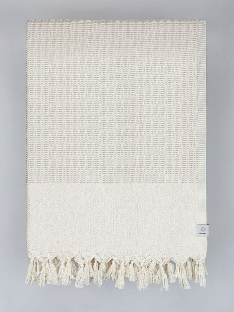 Folded soft cotton blanket with a gentle waves pattern in beige colour.